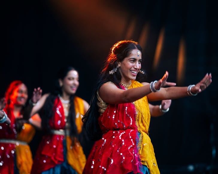 People in traditional attire dance Bollywood.