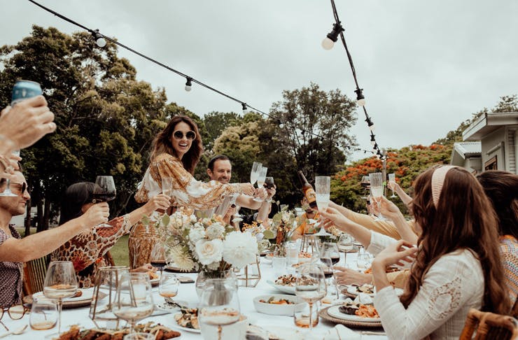 A party of people cheers around an outdoor table