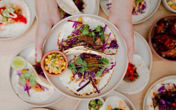 a plate of tacos being held above other plates of tacos