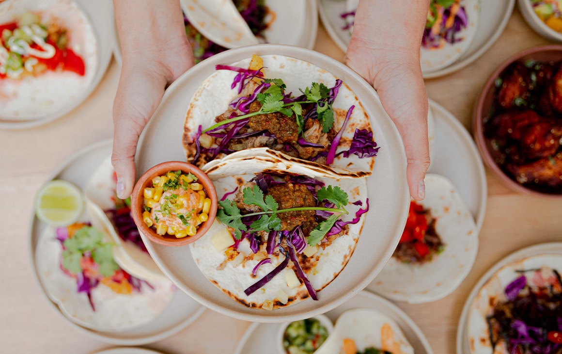 a plate of tacos being held above other plates of tacos