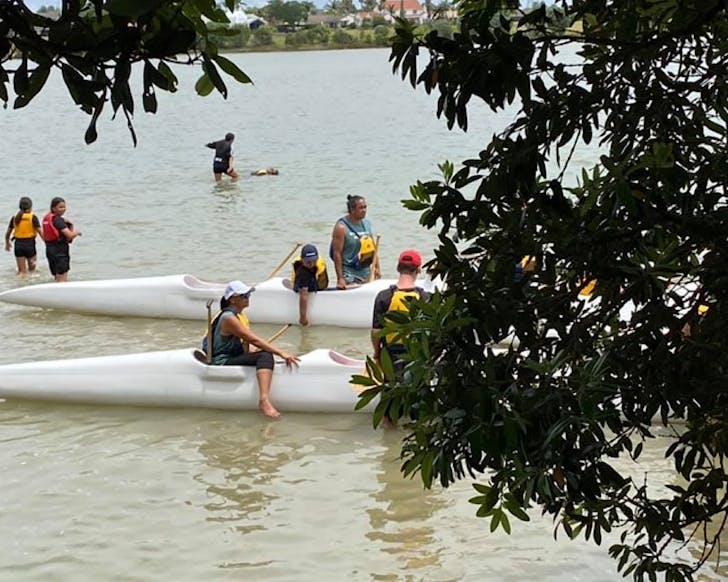 People climb into a double hull waka.