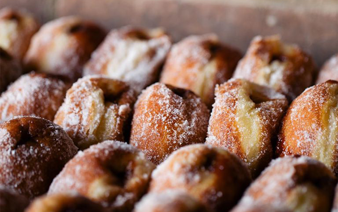 Several rows of filled, sugary doughnuts