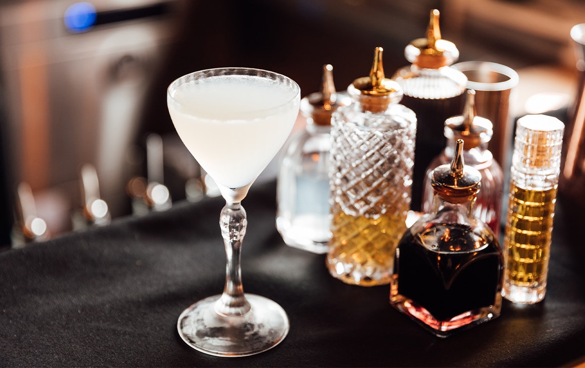 a gimlette cocktail next to small glass bottles