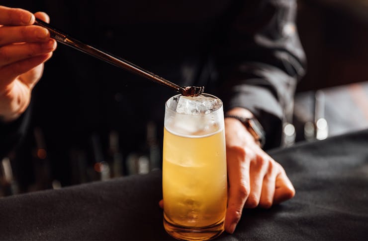 garnish being placed on top of a highball cocktail