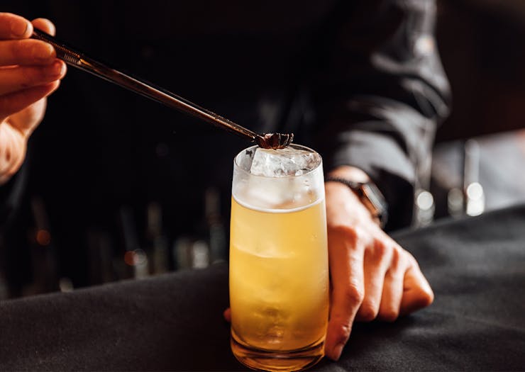 garnish being placed on top of a highball cocktail