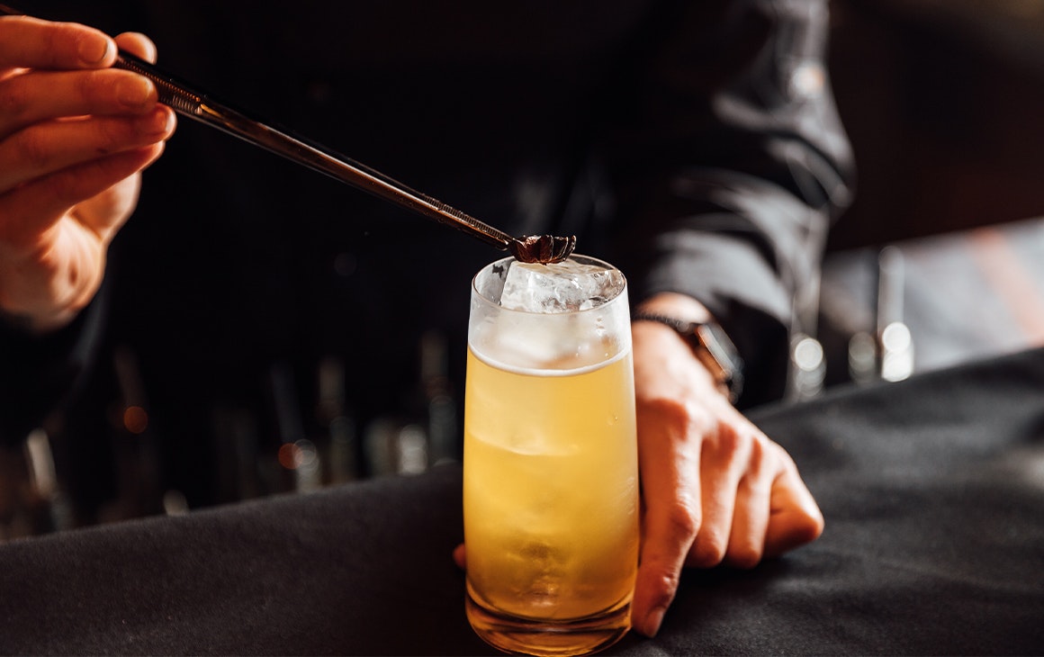 garnish being placed on top of a highball cocktail