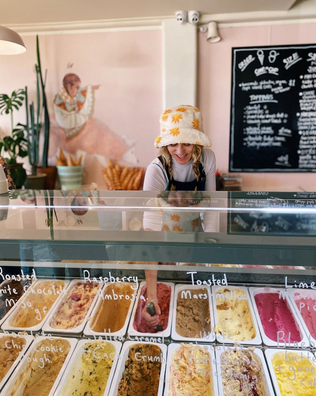 A girl in a sunny hat scoops at Duck Island Ice Cream.