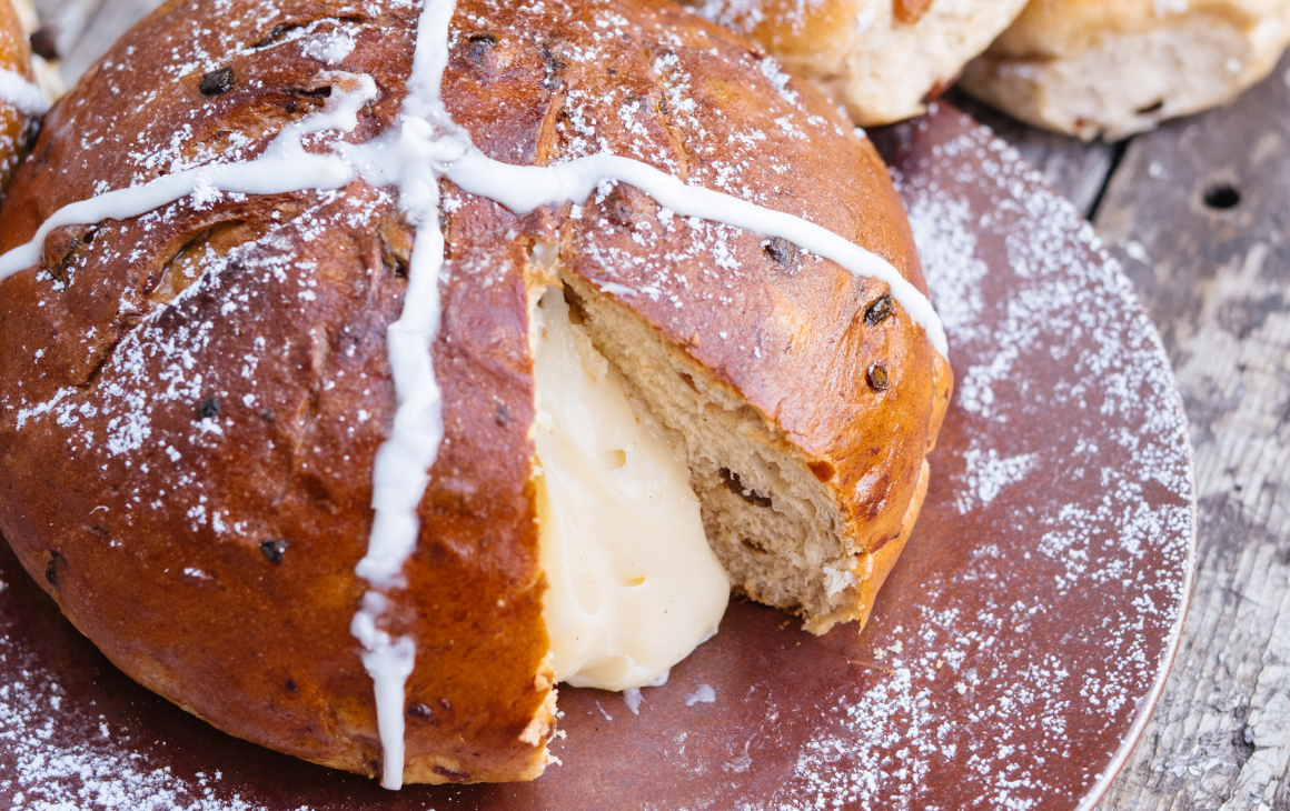 a giant hot cross bun with creamy filling oozing out