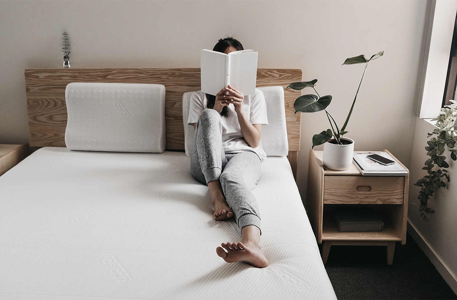 A woman sits on a bed.
