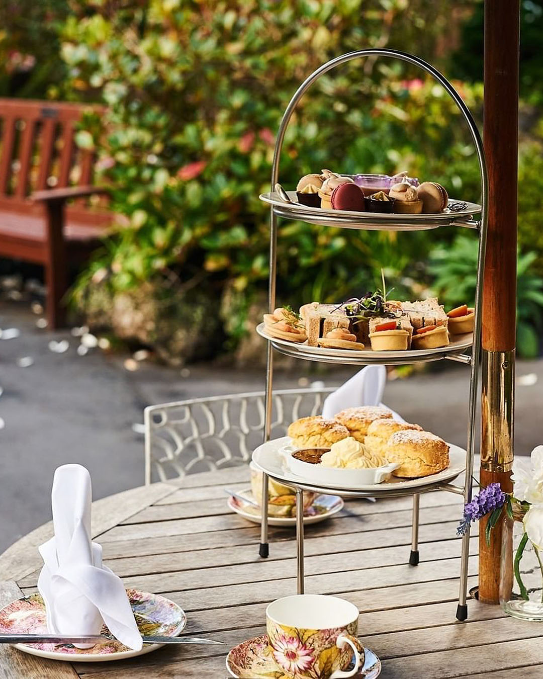 The afternoon tea at Eden Garden laid out on a table with a garden bench in the background.