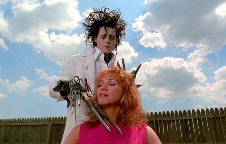 Johnny Depp as Edward Scissorhands gives a lady a hair cut in the garden.