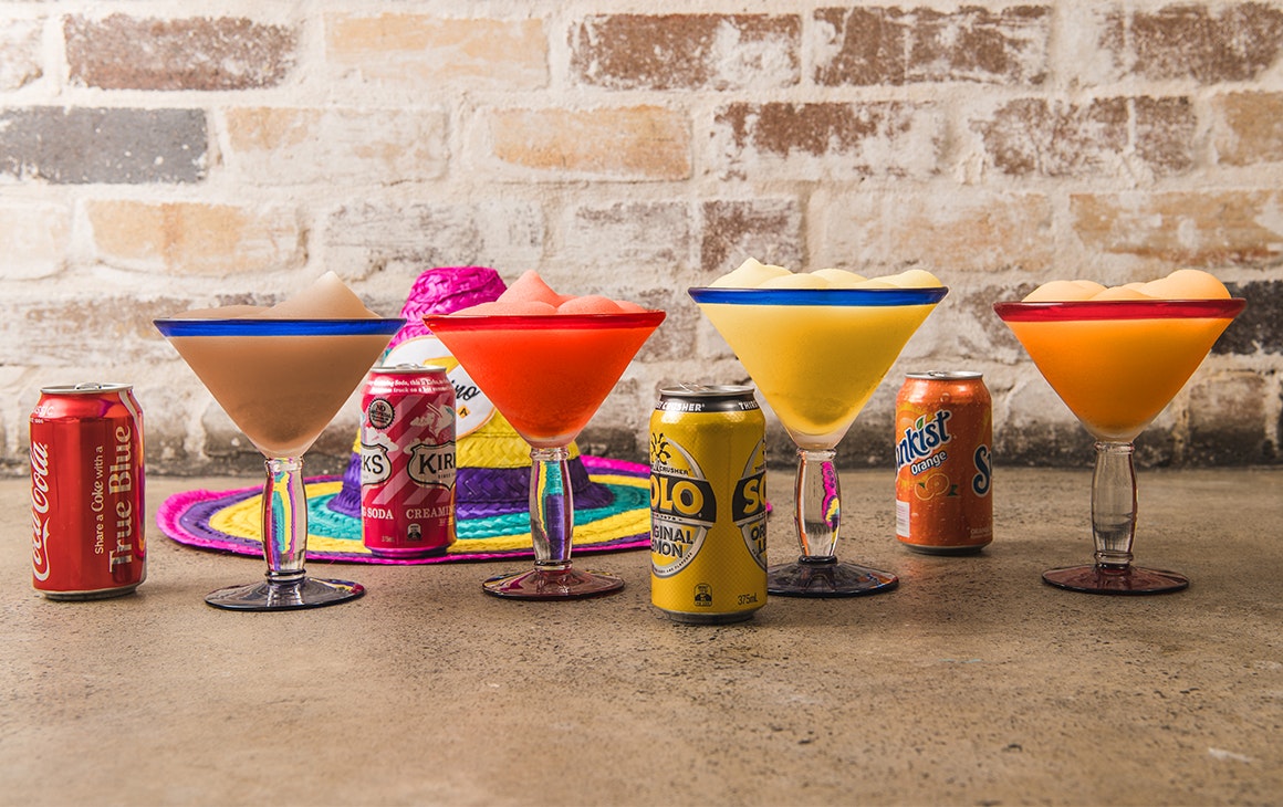 a row of frozen margaritas with soft drink cans alongside