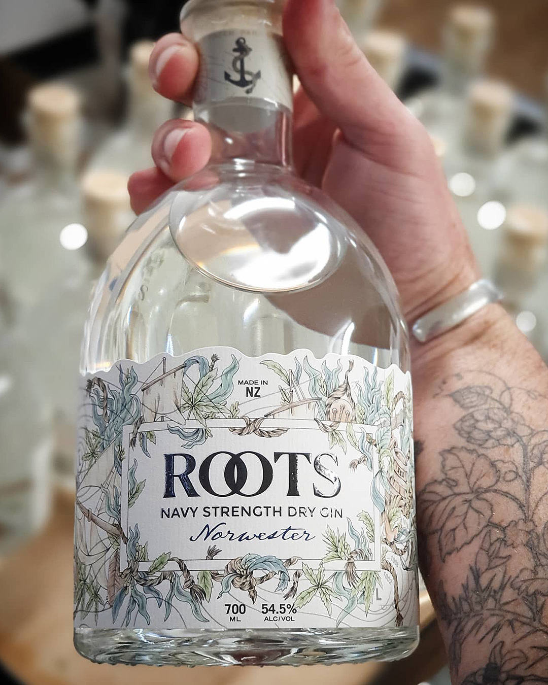 Someone holds a bottle of Elemental Distillers' Roots gin, one of the best gins in NZ.