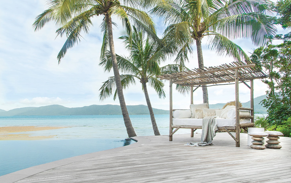 A day bed sitting on a deck next to the pool overlooking the ocean at Elysian Retreat