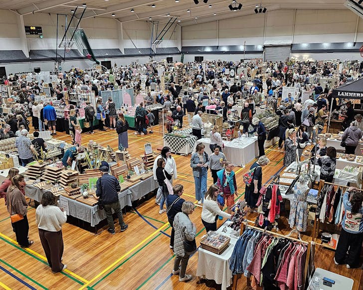 Crowds of people peruse the indoor Encraftment Market inside a gymnasium.