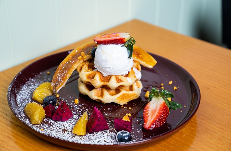 a plate of waffles topped with fruit