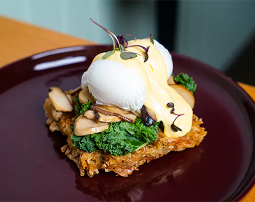 a potato waffle topped with eggs, kale and mushroom