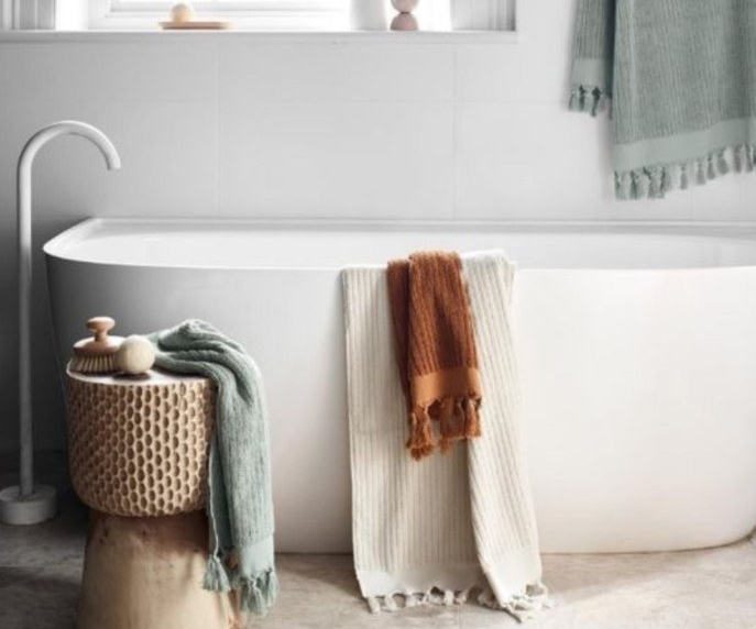 A bathtub draped with towels from Aura home which are currently on sale for EOFY