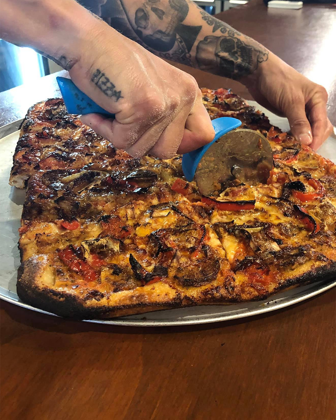 A hand slices a delicious looking pizza at Epolito's.