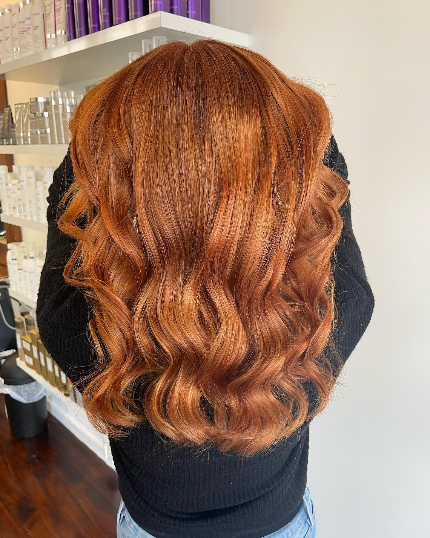 A woman with freshly cut, ginger red wavy long hair done at Escada Hair salon, one of the best hairdressers in Tauranga.