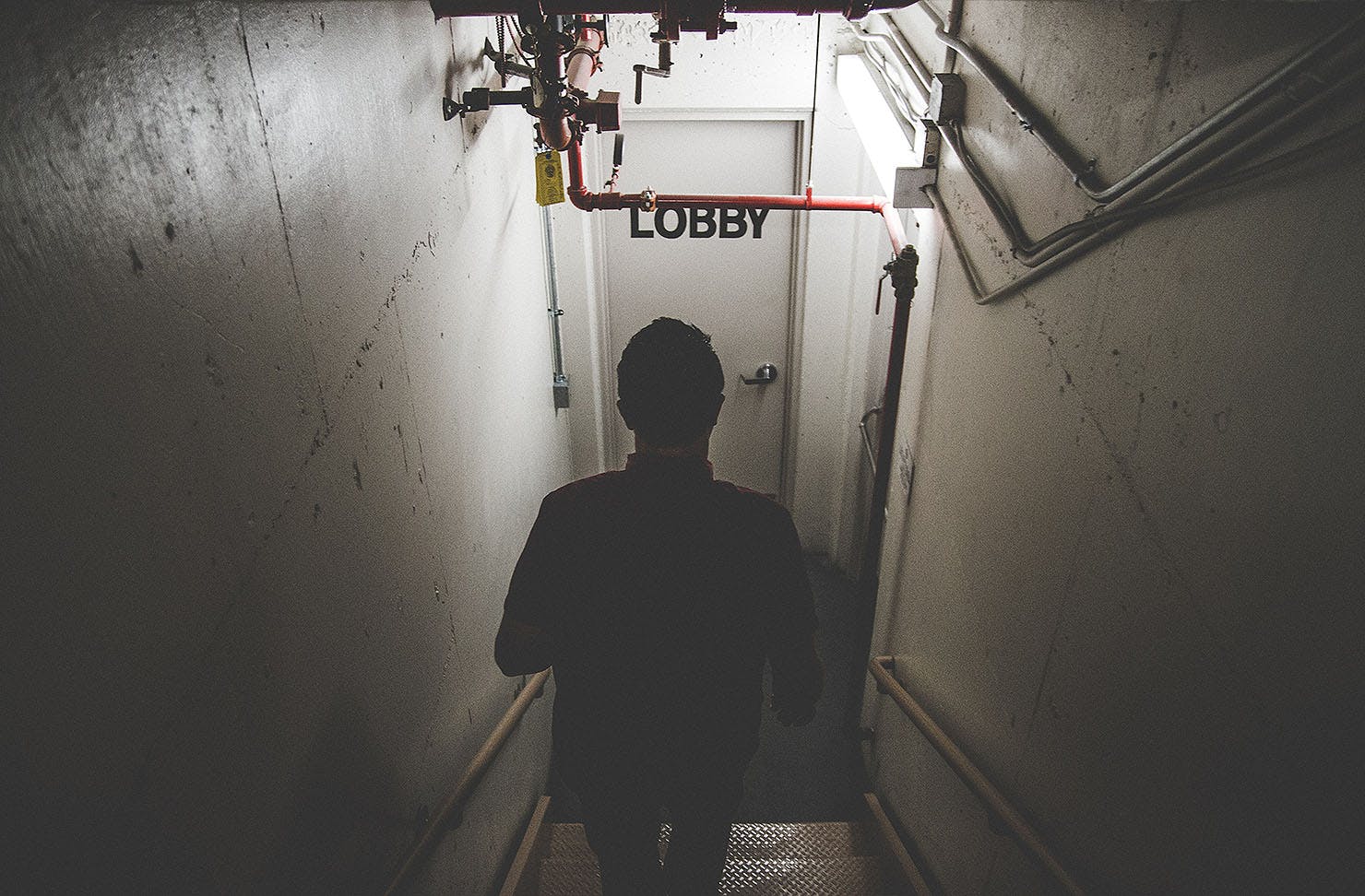 Someone walks down some stairs towards a door labelled Lobby. These are the best escape rooms in Christchurch.