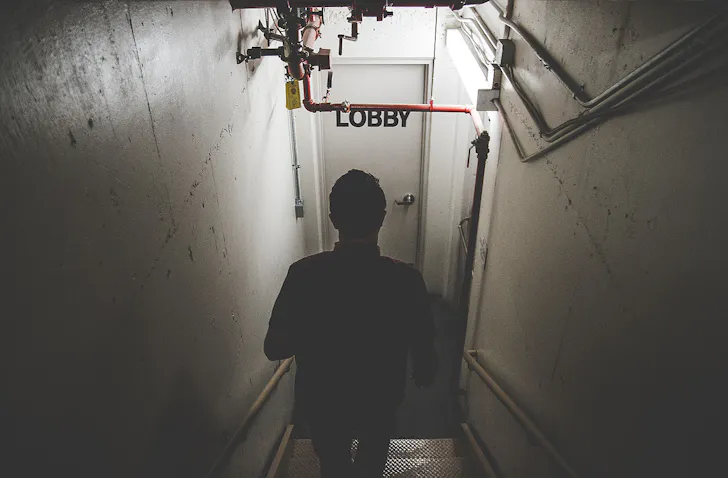 Someone walks down some stairs towards a door labelled Lobby. These are the best escape rooms in Christchurch.