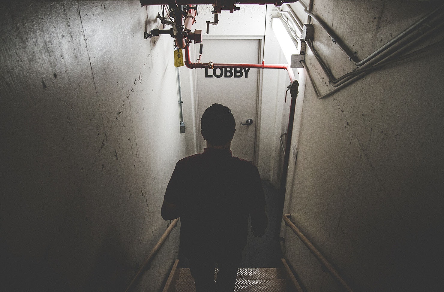 Someone walks down some stairs towards a door labelled Lobby. These are the best escape rooms in Christchurch.