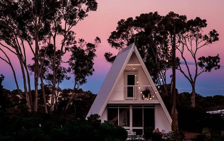 a small white cottage set amongst treets at sunset