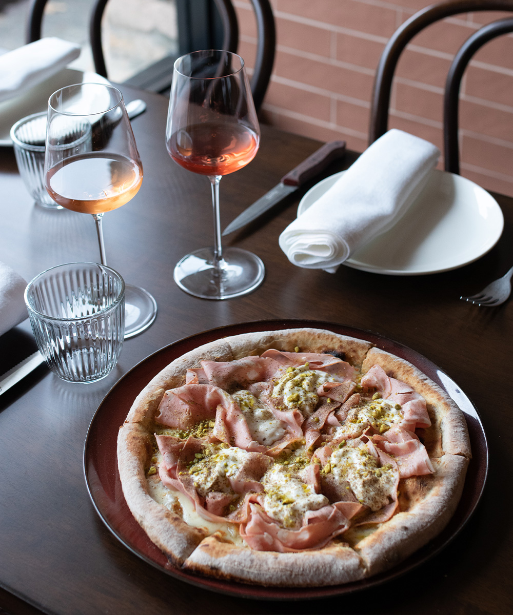 a pizza on a table with a glass of wine