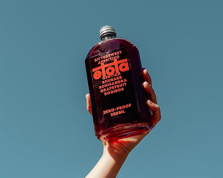 Someone holds up a bottle of Etota, one of the best non-alcoholic drinks in Australia.