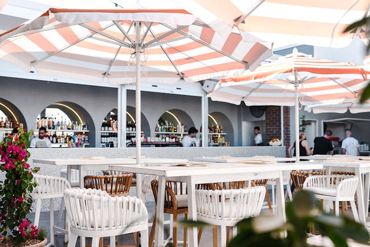 a bar area with striped umbrellas above tables