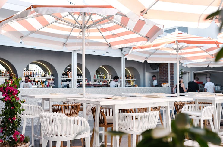 a bar area with striped umbrellas above tables