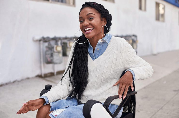 A girl in a wheelchair looks very happy in her cool new Tommy Hilfiger adaptive threads.