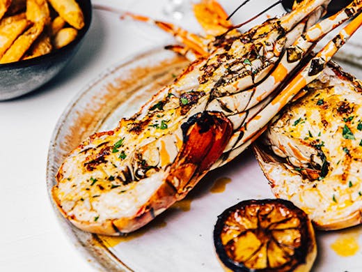 grilled lobster on a plate drizzled in melted butter