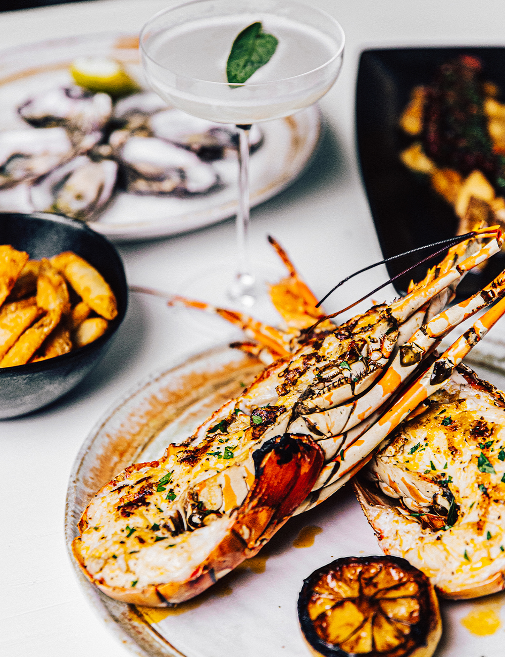 a plate of lobster drizzled with butter on a table full of food