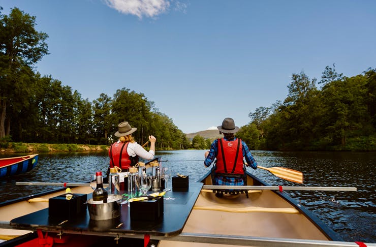 A couple canoe in Kangaroo Valley on a custom-built canoe topped with drinks and capaes. 