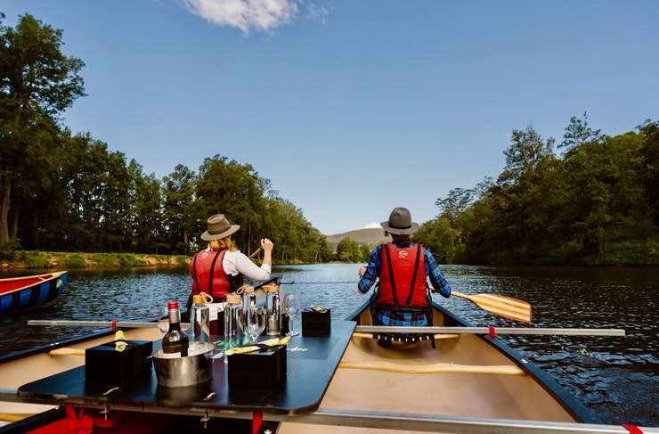 A couple canoe in Kangaroo Valley on a custom-built canoe topped with drinks and capaes. 
