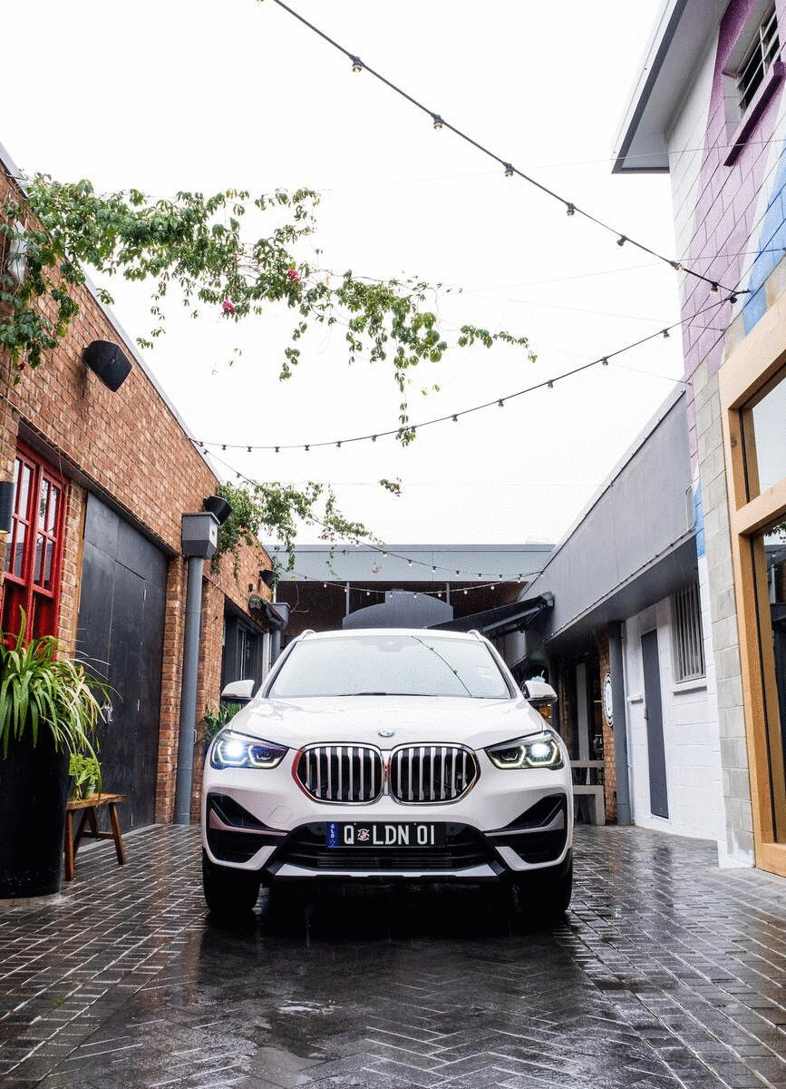 A BMW car is parked in a European-looking laneway.
