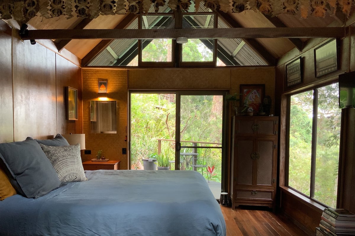 a bed in a cabin overlooking a rainforest