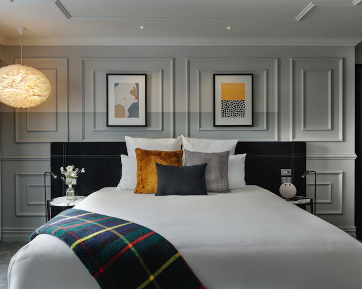 An elegant guest suite at the Fable hotel in Dunedin, featuring a plush bed with a tartan throw