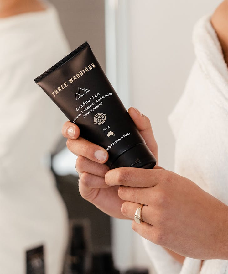 a hand holding a tube of fake tan cream