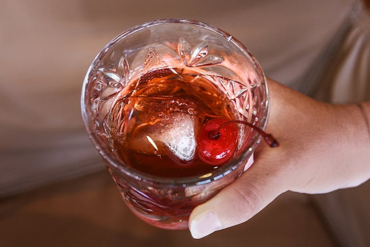a hand holding a cocktail in a short glass
