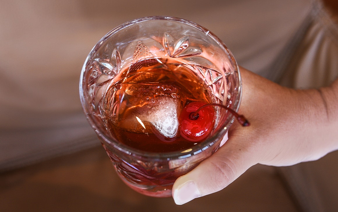 a hand holding a cocktail in a short glass