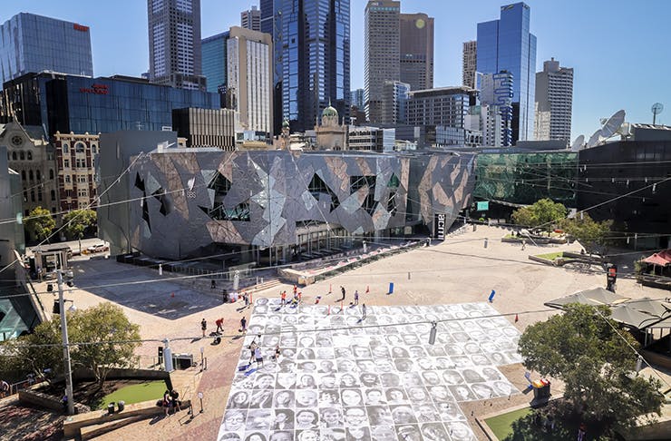 Fed Square with thousands of printed face on the ground.