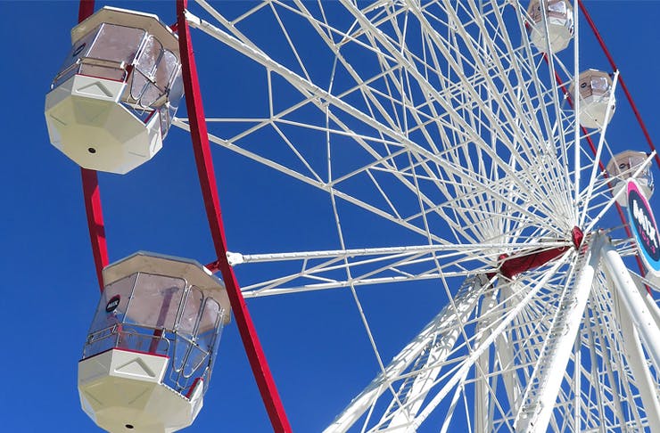 Looking up to the sky and a white ferris wheel.