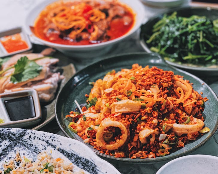 Hands grabbing noodles in bowl with chopsticks