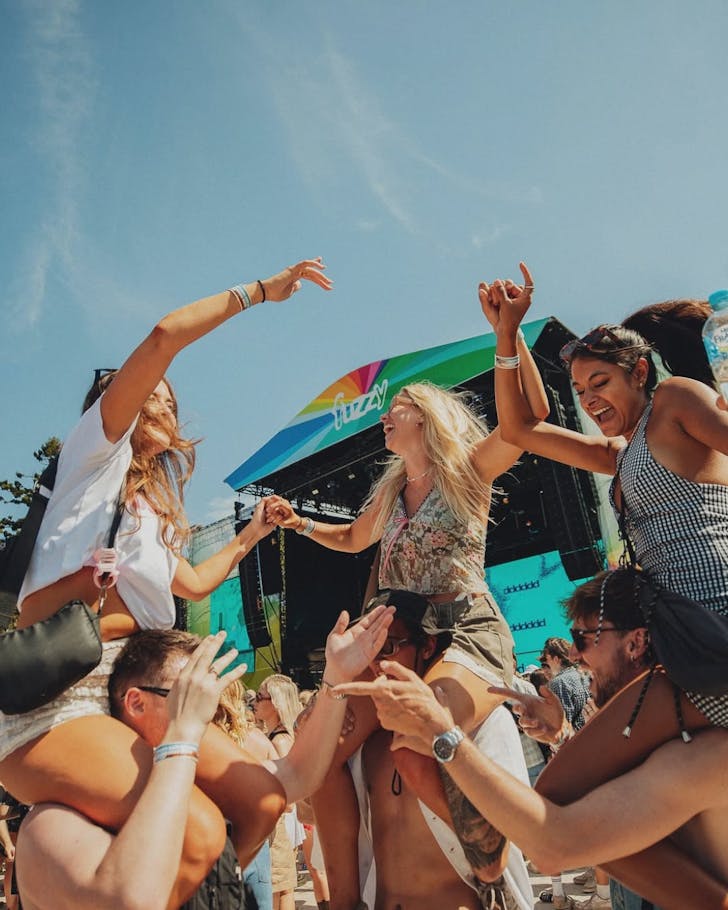 Three women dance on top of the shoulder's of their friends at Field Day
