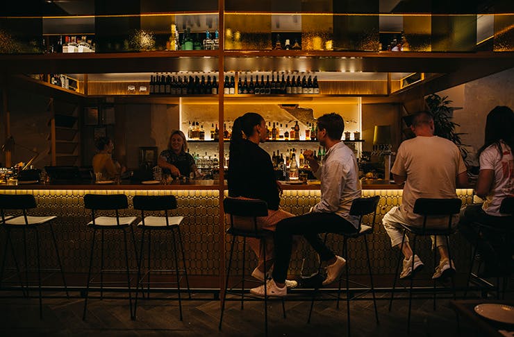 A dimly lit restaurant with two people dining together under red light.