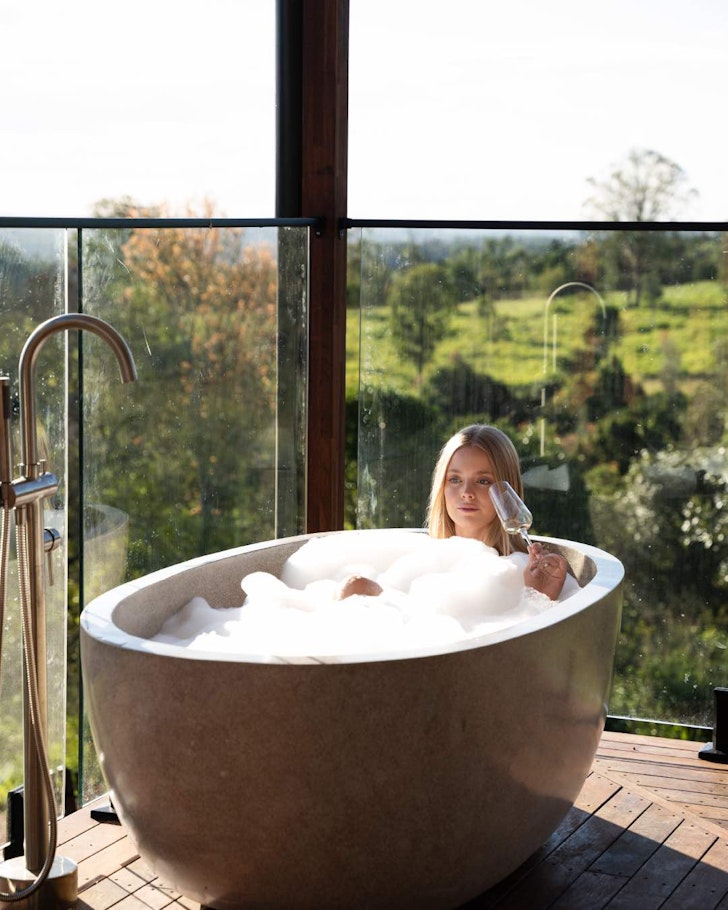A woman lies in an outdoor bath at The Firebreak near Brisbane Queensland