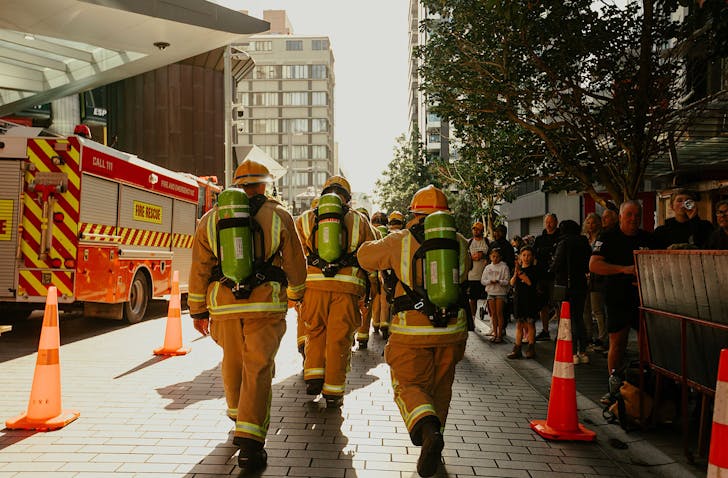 A bunch of firefighters walk towards the Sky Tower. 